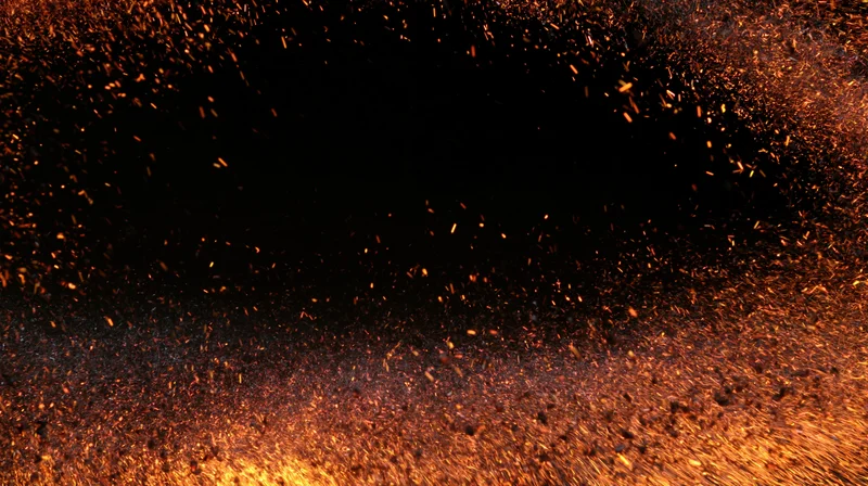 Glowing sparks and embers scattered across a dark background with copyspace