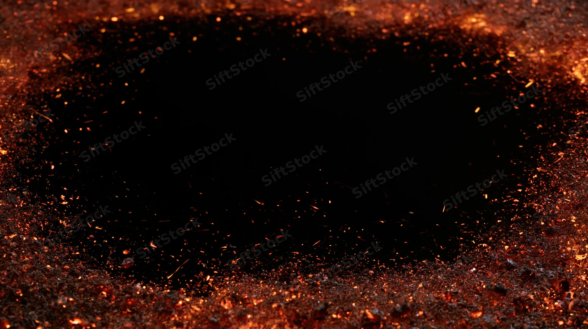 Glowing embers and sparks scattered across a dark surface with a central black void