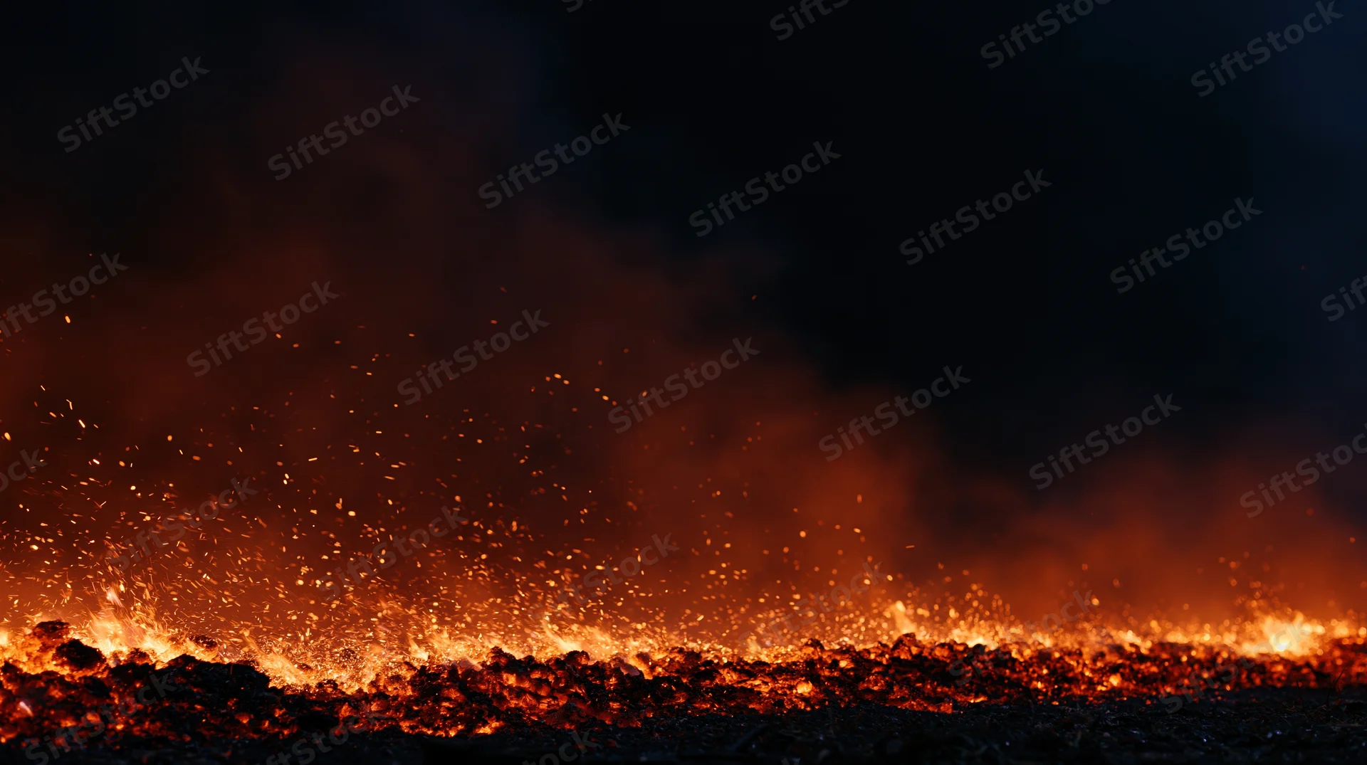 Low flames and flying embers burning along the bottom edge at night