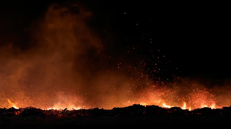 Low flames and flying embers burning along the bottom edge at night