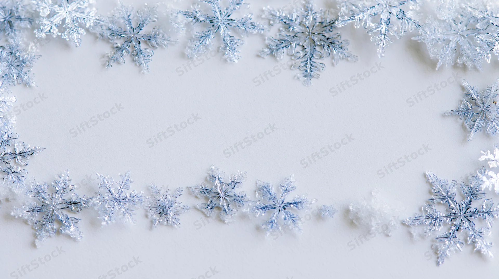 Snowflakes arranged in a border frame on white surface with copyspace