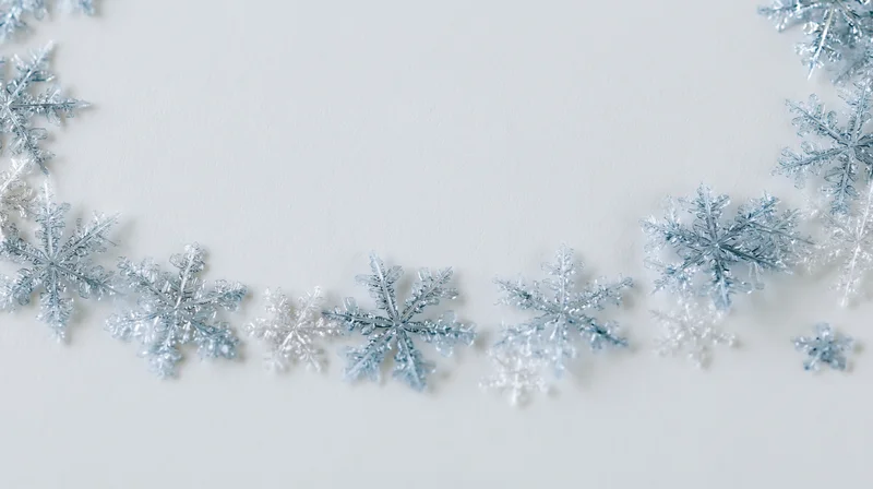 Glittery snowflakes arranged in a border on white surface with copyspace