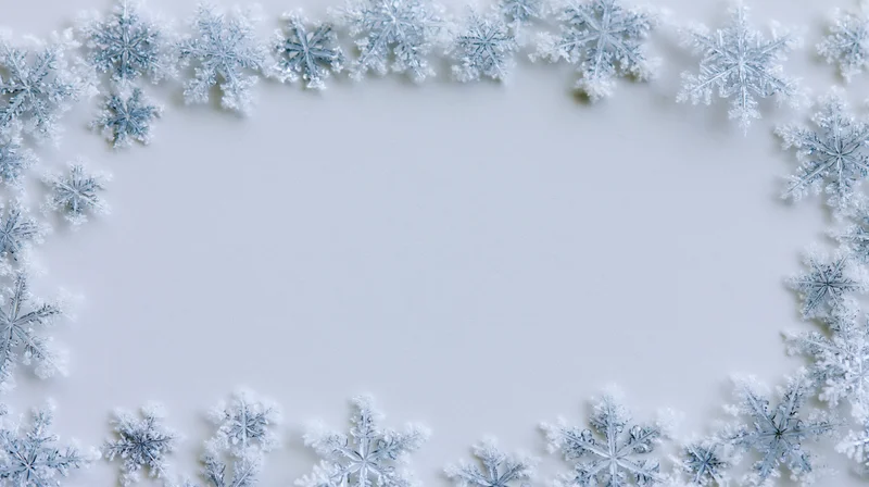 Snowflakes arranged in a border frame on a white surface with copyspace in the center