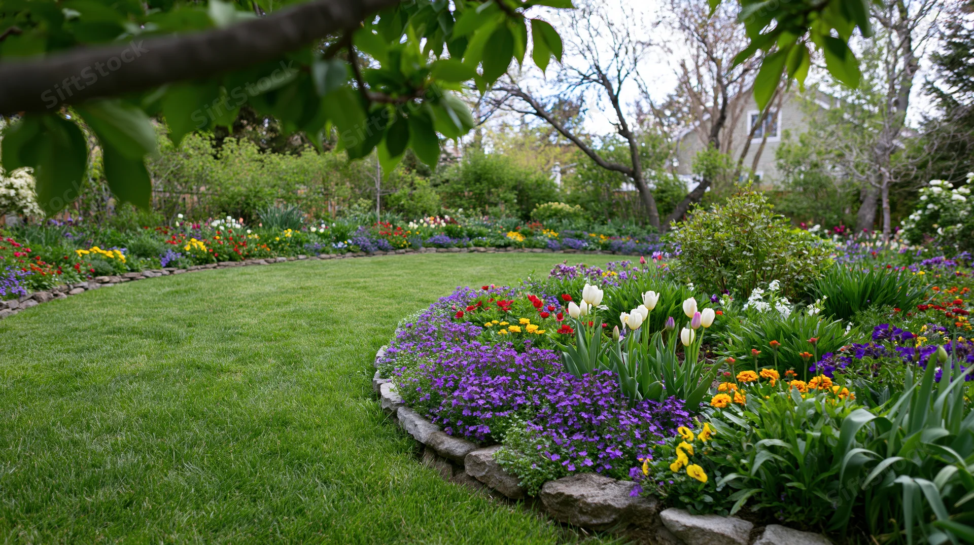 Curved lawn bordered by colorful flowerbeds in a manicured backyard garden