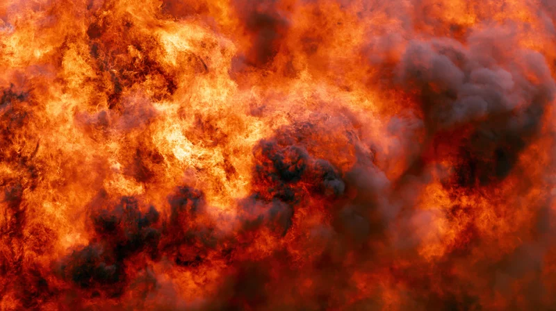 Massive wall of fire filling the frame in extreme close-up with intense orange and red flames and dark smoke