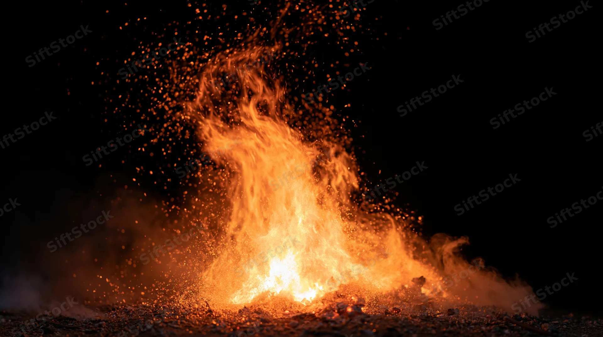Flames bursting upward with flying sparks against a black background