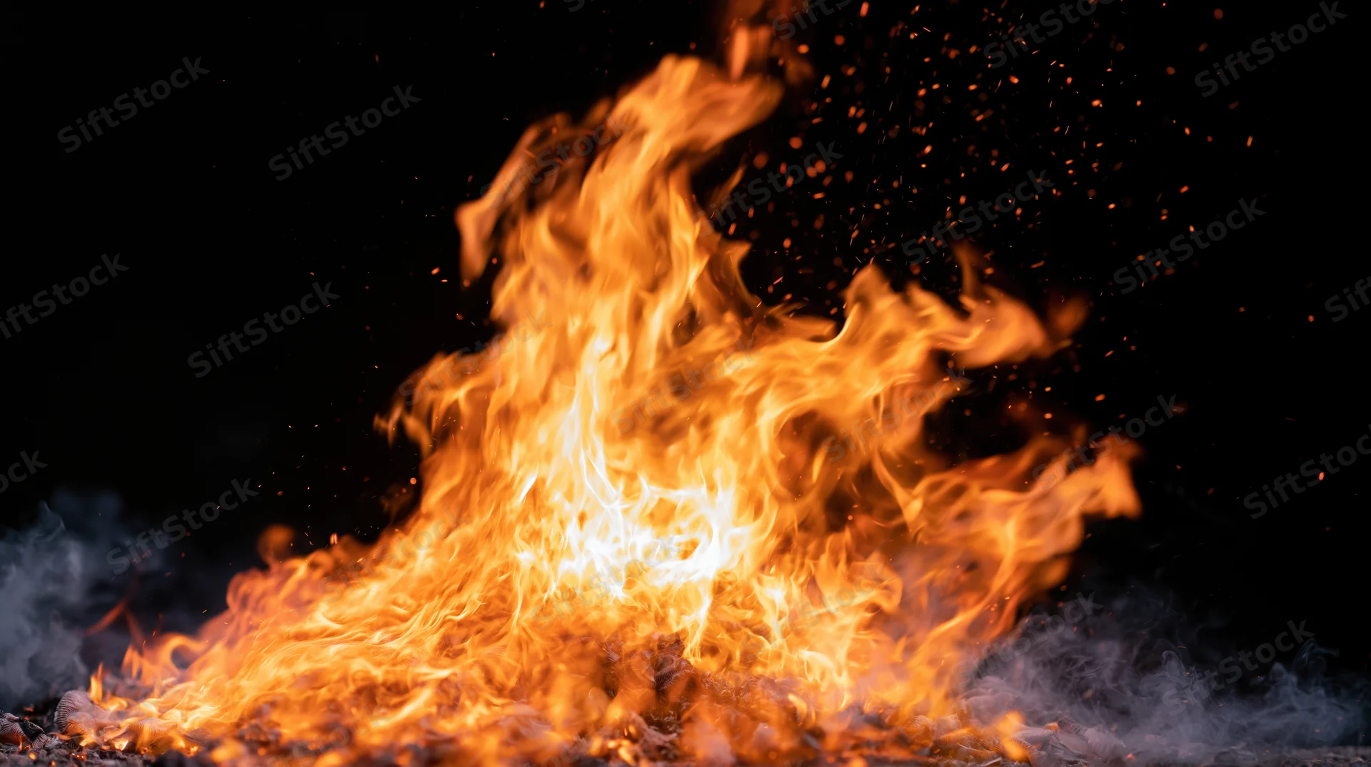 Intense flames burning with sparks and smoke against a black background