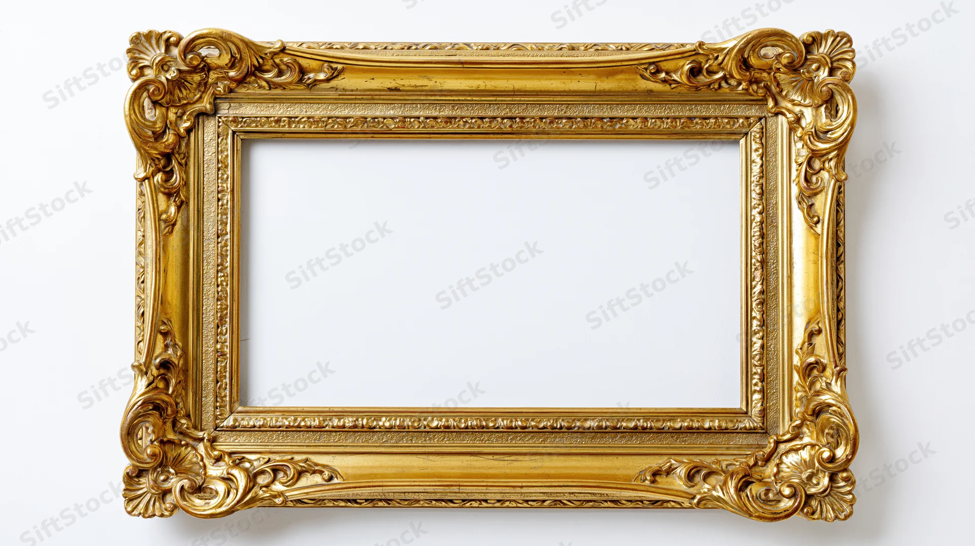 Ornate baroque gilt picture frame with carved scrollwork hanging on white wall