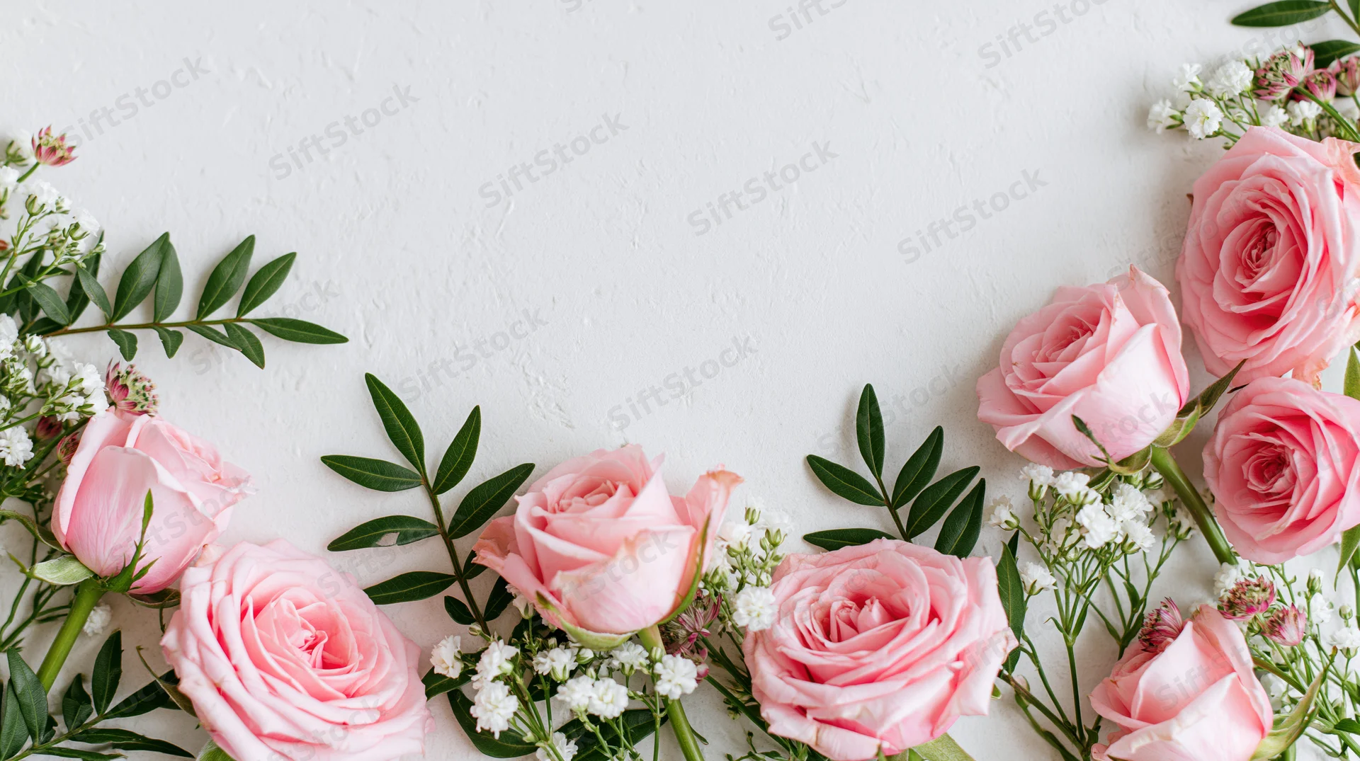 Pink roses and white blooms with green foliage arranged in a flat lay on white surface