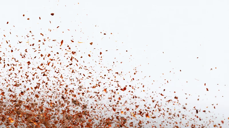 Orange fire embers and sparks floating mid-air against white background