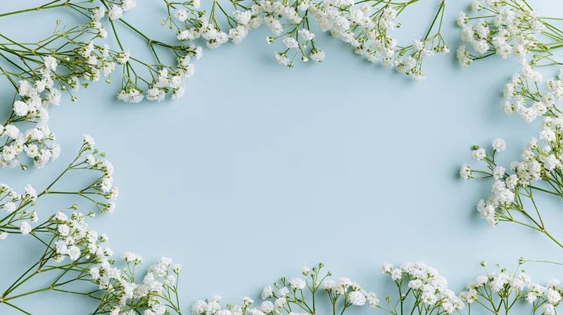 White gypsophila sprigs arranged as a border on a light blue surface with copyspace