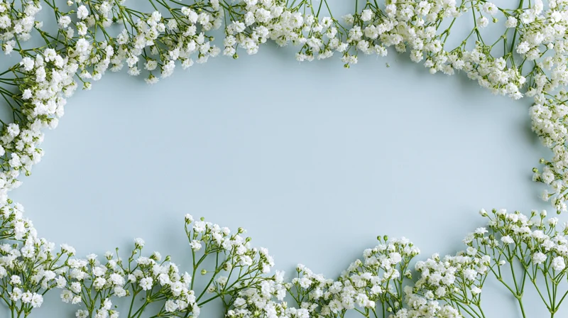 White gypsophila sprigs arranged as a border on a light blue surface with copyspace