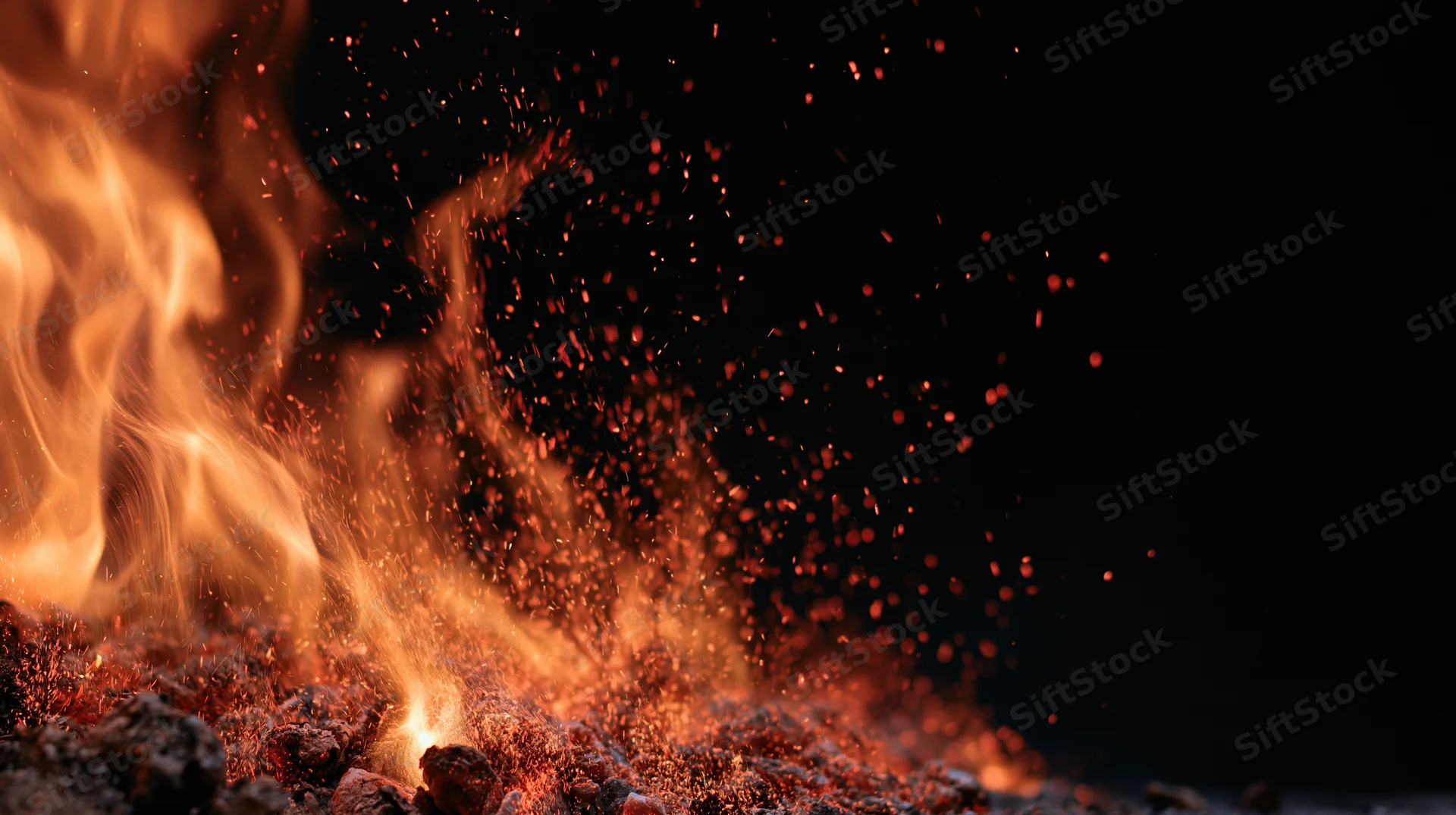 Flames and glowing embers rising from burning coals against a dark background
