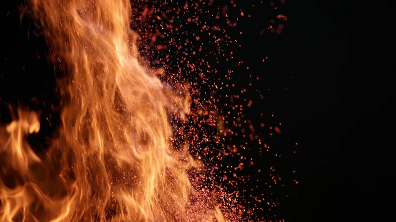 Tall flames and glowing embers rising against a black background