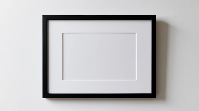 Black rectangular picture frame with white mat hanging on a plain wall