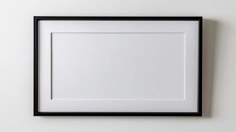 Black rectangular frame with white mat hanging on a plain wall