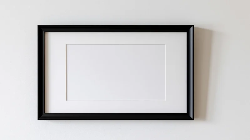 Black rectangular frame with white mat mounted on white wall, empty interior for display
