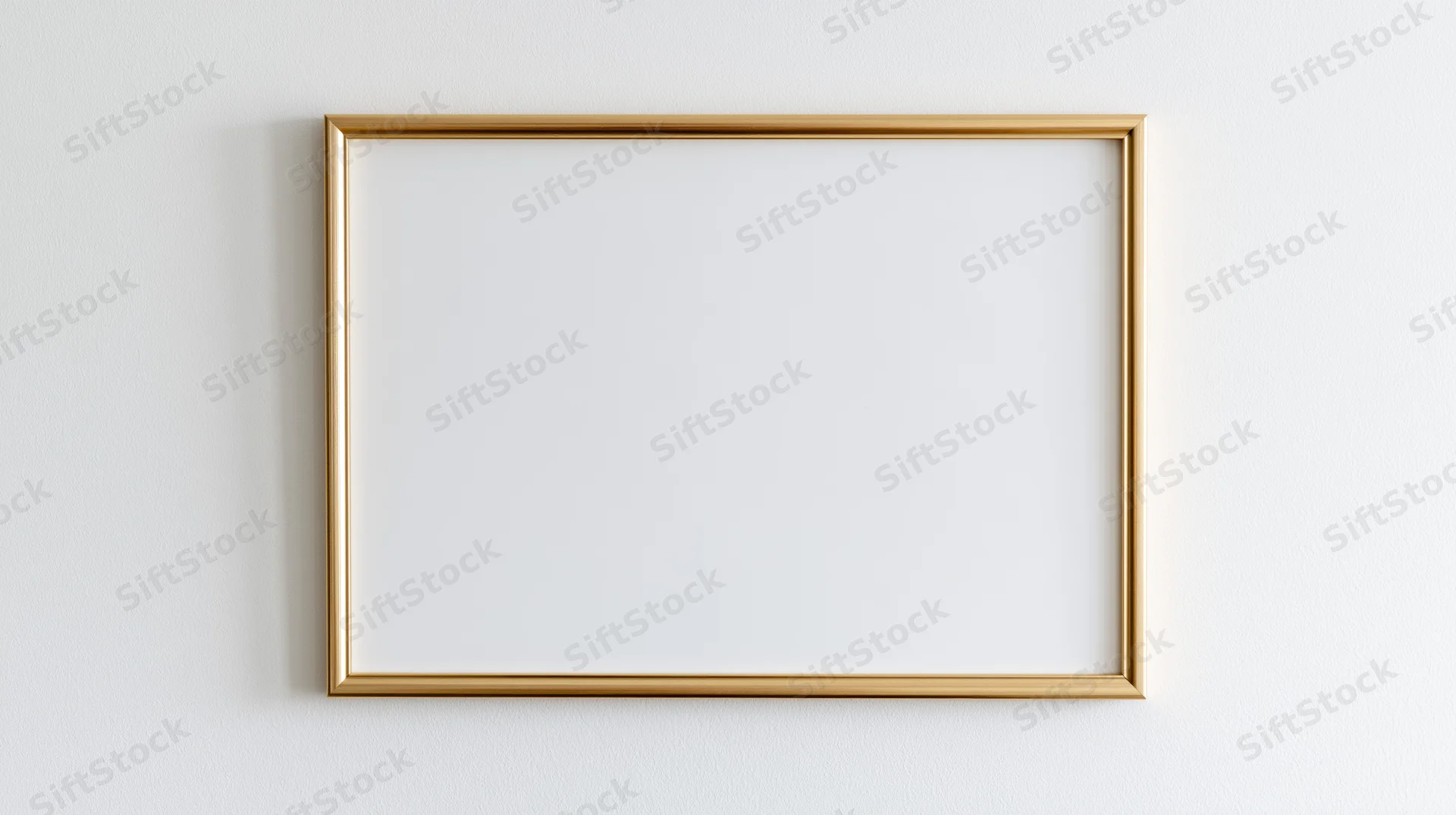 Thin gold metal picture frame with empty white interior hanging on a white wall