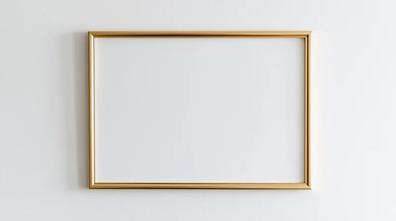 Thin gold metal picture frame with empty white interior hanging on a white wall
