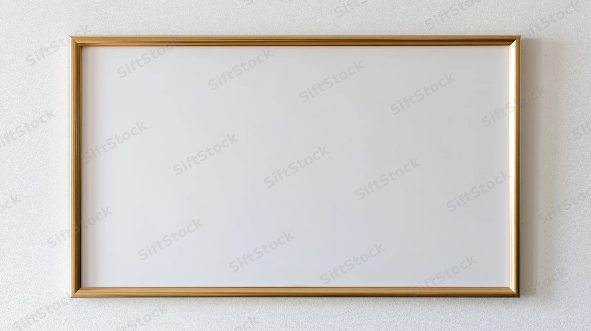 Thin gold metal picture frame with empty white interior hanging on a white wall