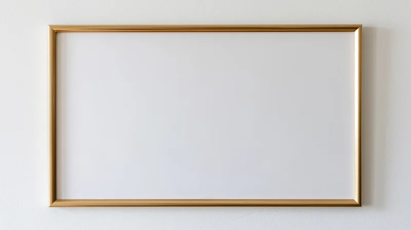 Thin gold metal picture frame with empty white interior hanging on a white wall