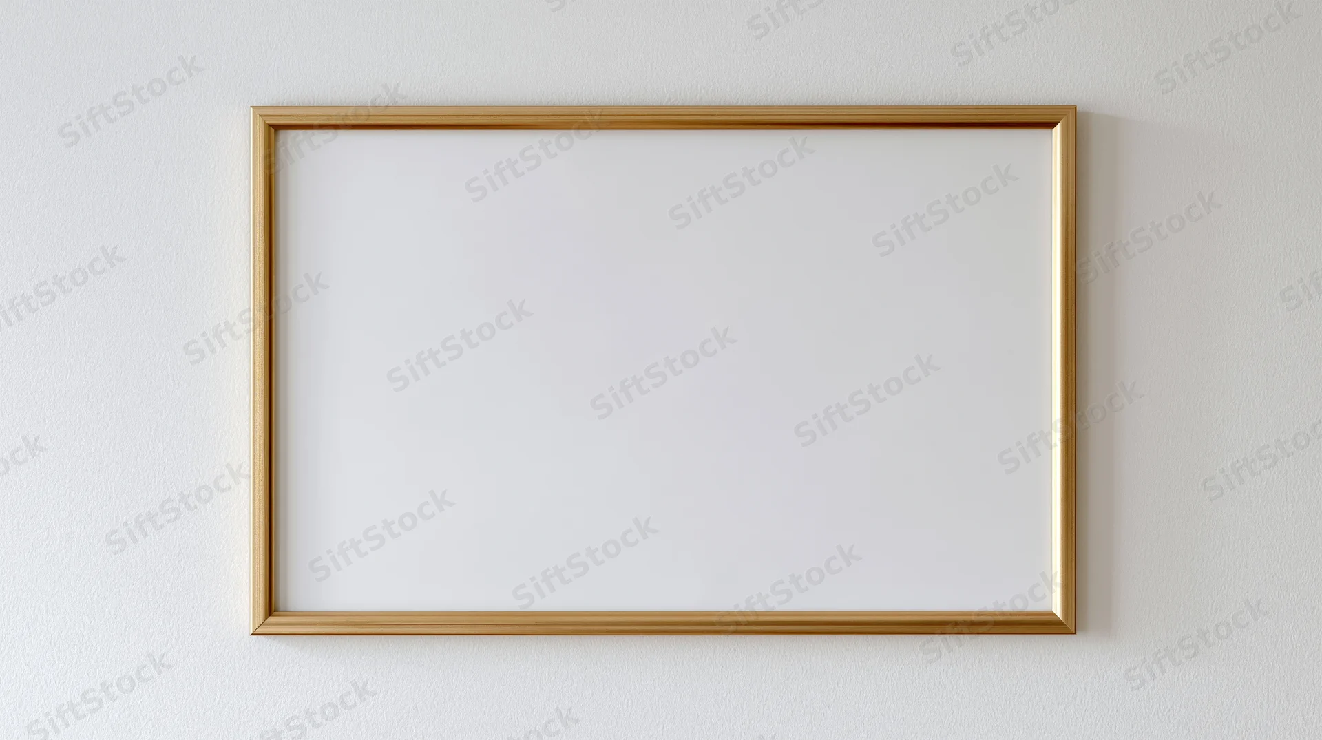 Thin gold metal picture frame with empty white interior hanging on a white wall