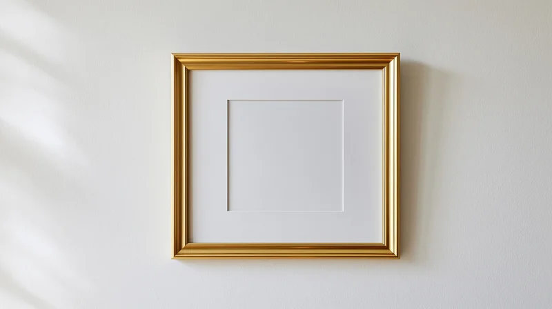 Gold picture frame hanging empty on white wall with shadow and copyspace