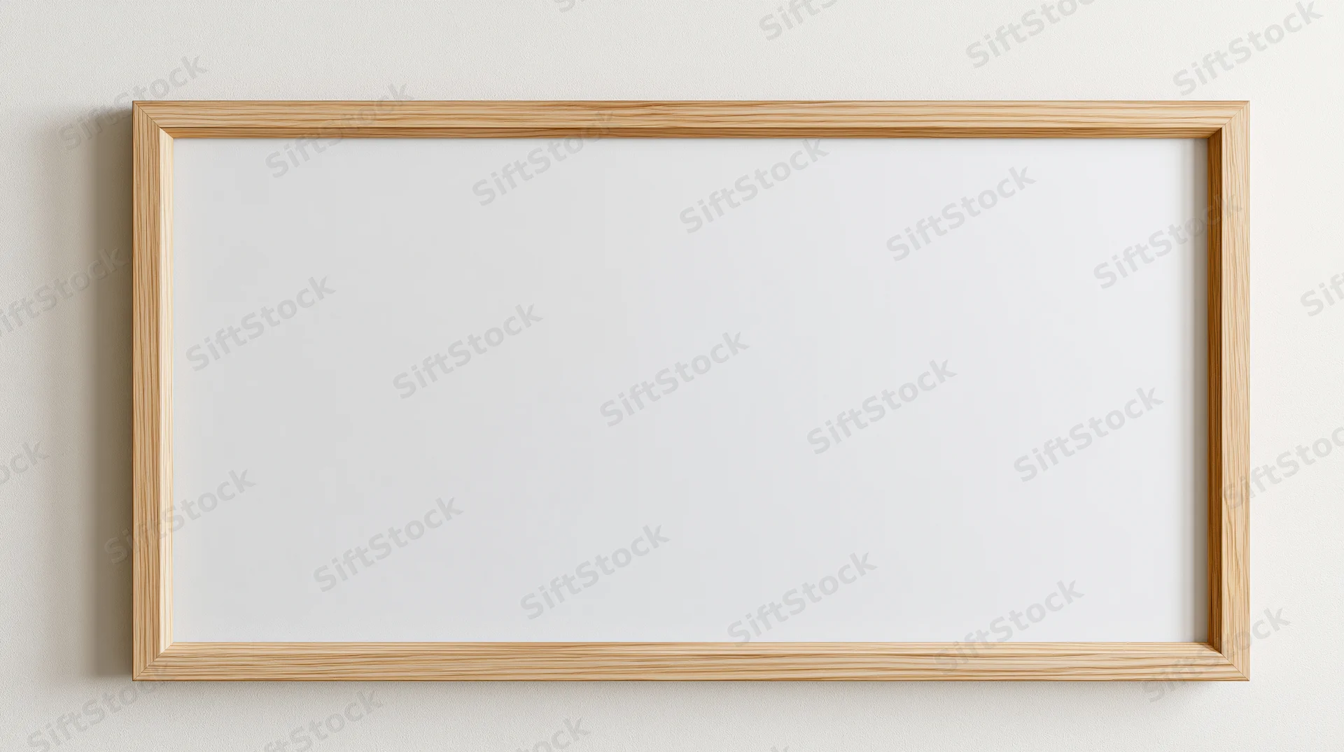 Light oak wooden picture frame with blank white interior hanging on a wall