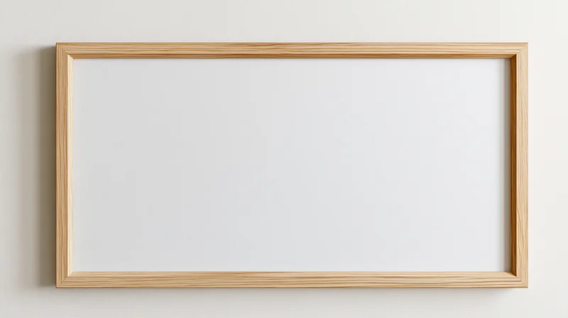 Light oak wooden picture frame with blank white interior hanging on a wall