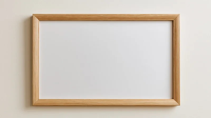 Light oak wooden picture frame with blank white interior hanging on a beige wall