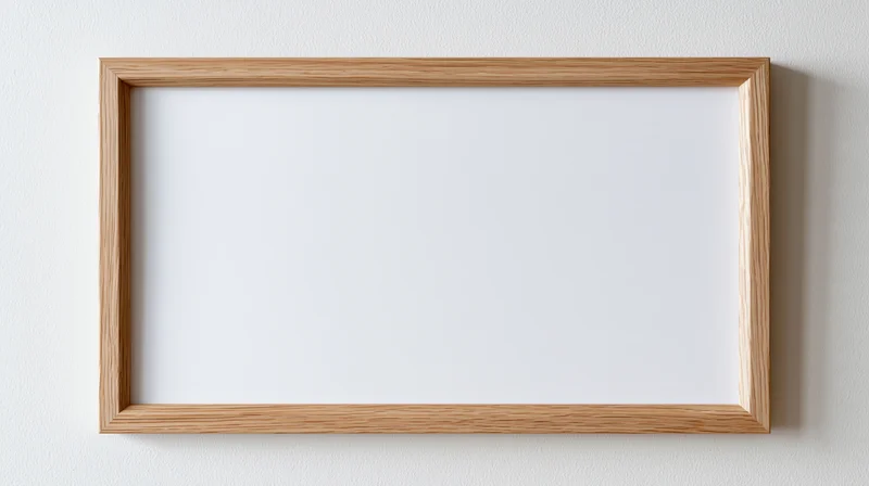Light oak wooden picture frame with blank white interior hanging on a white wall