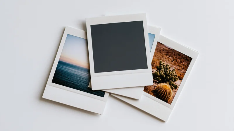 Three polaroid instant photo prints fanned out on white surface with blank center print and scenic images of ocean sunset and desert cactus