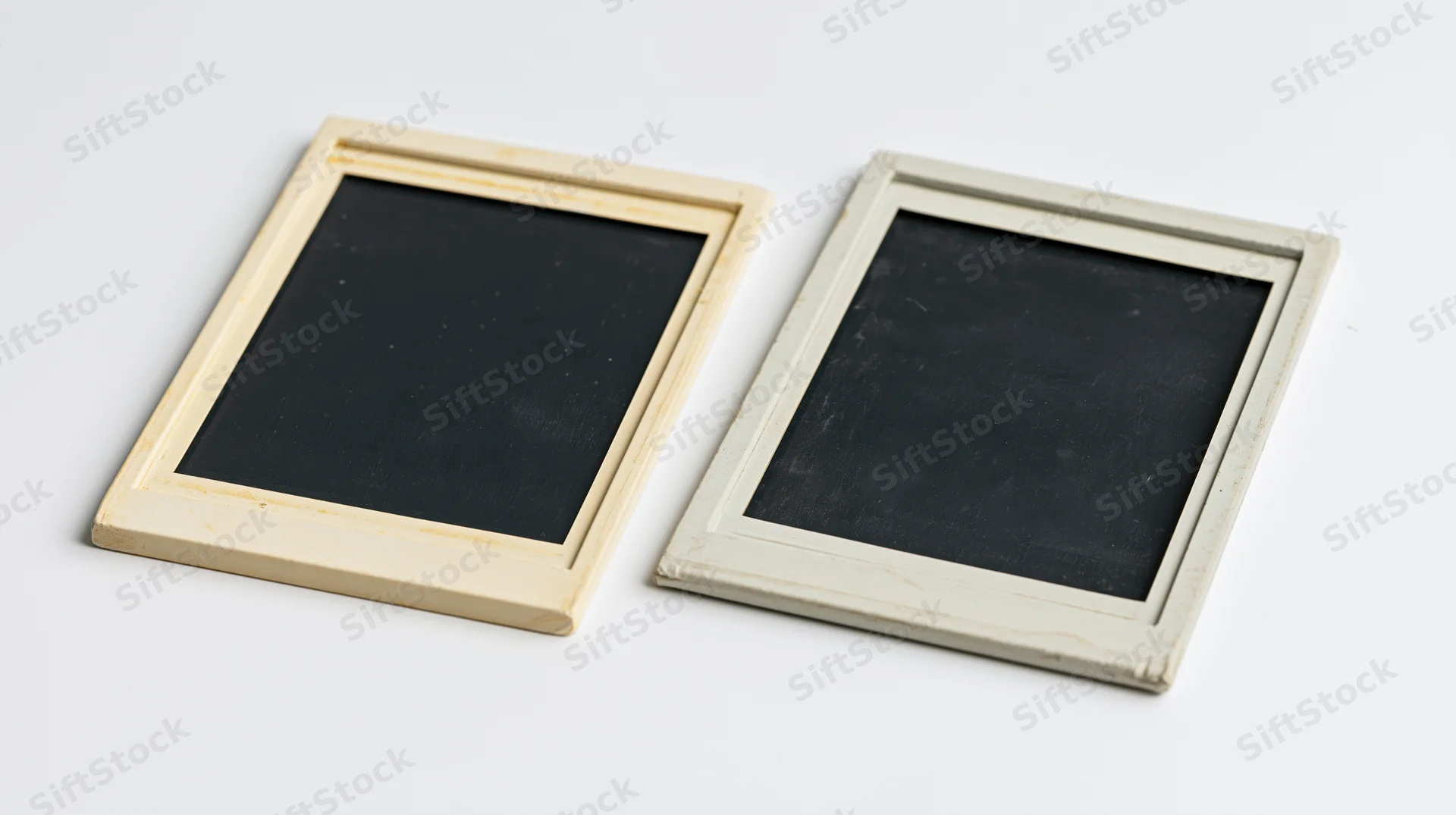Two blank chalkboards in wooden frames on a white surface