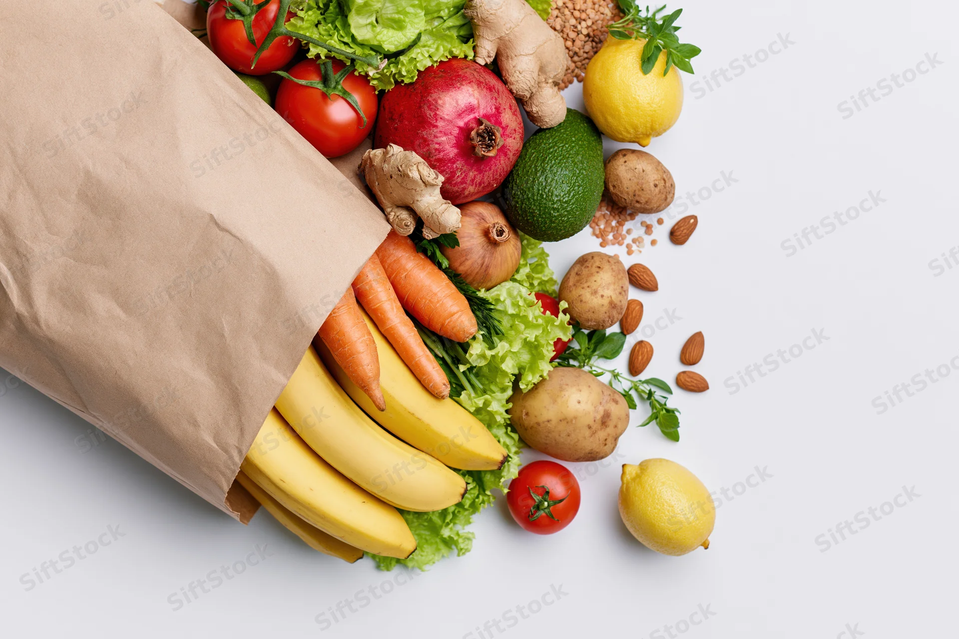 Kraft paper grocery bag tipped on its side with fresh produce spilling out onto white surface