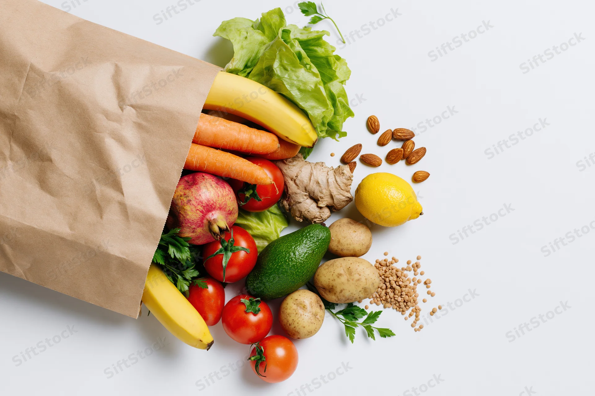 Kraft paper grocery bag tipped on its side with fresh produce spilling out onto white surface