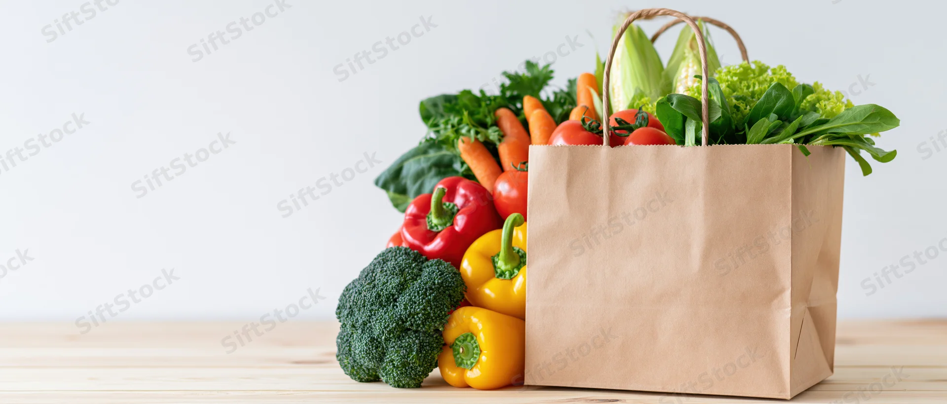 Kraft paper bag overflowing with fresh vegetables on wooden surface