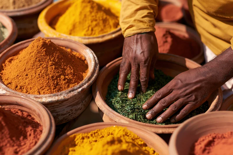 Man arranging dried herbs and spices in clay bowls at outdoor market
