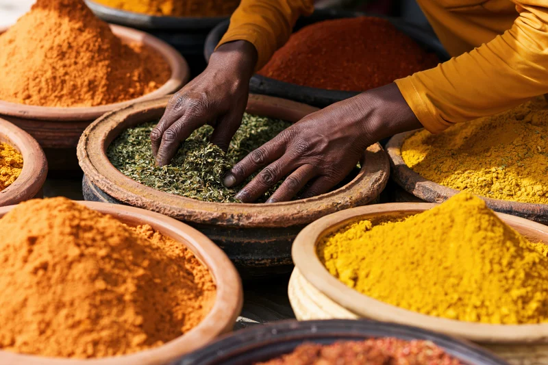 Vendor arranging dried herbs and spices in clay bowls at a market stall