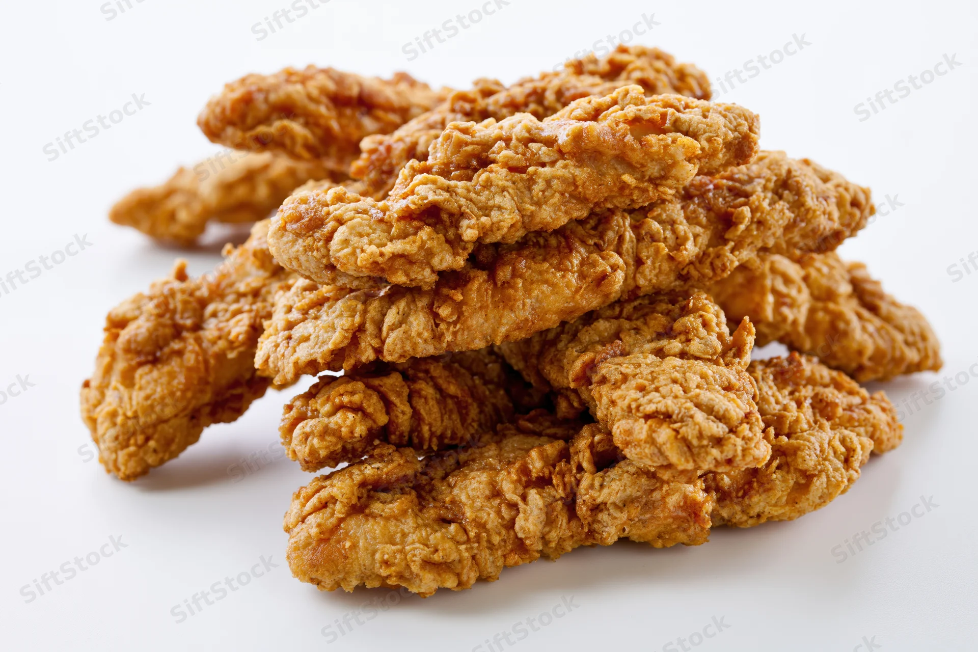 Crispy fried chicken tenders stacked loosely on a white surface