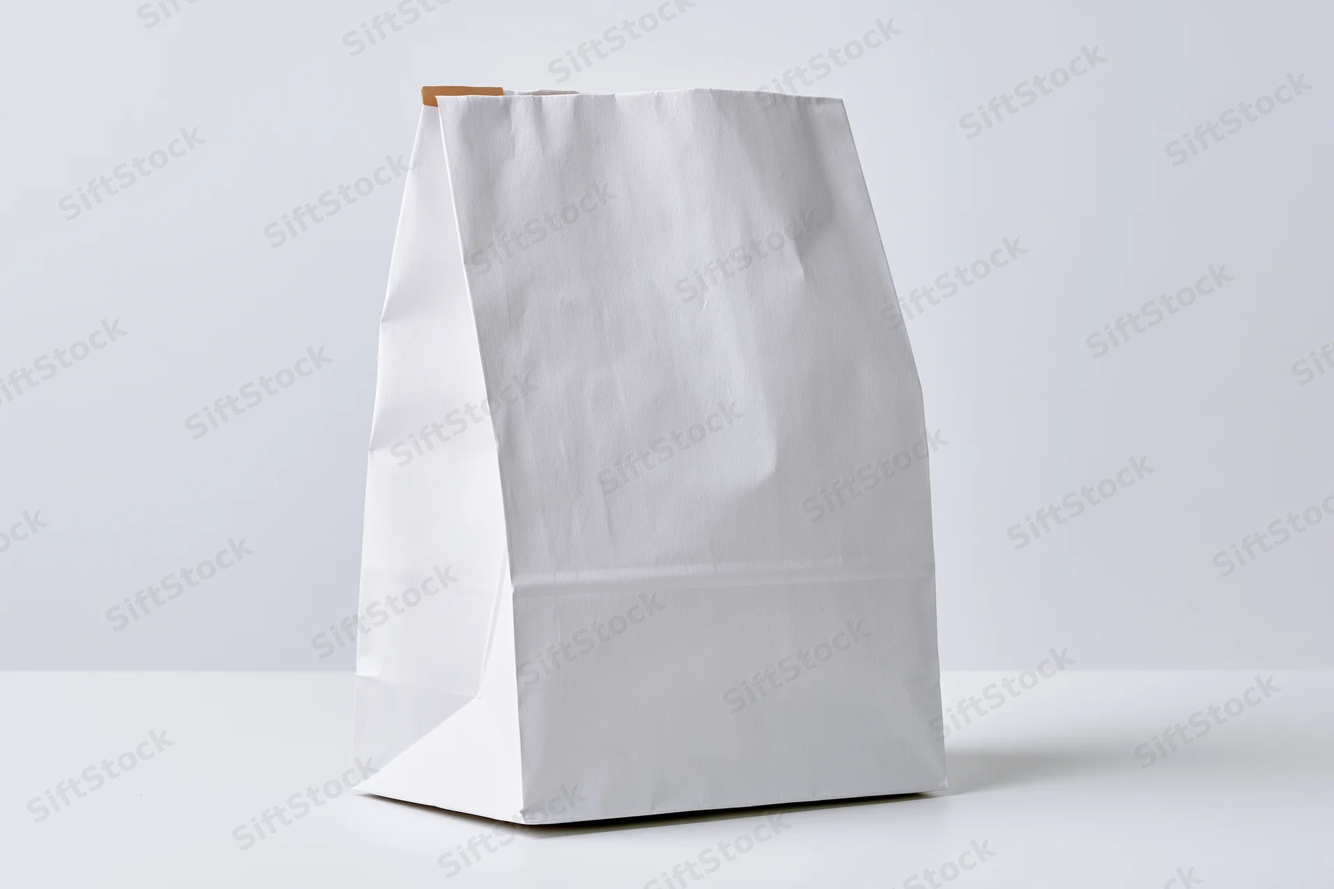 White paper bag standing upright on a flat surface with copyspace for branding