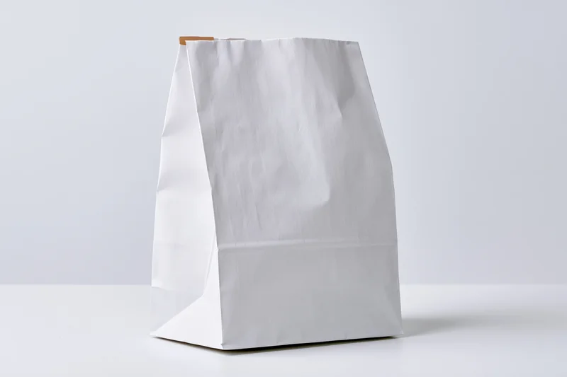 White paper bag standing upright on a flat surface with copyspace for branding