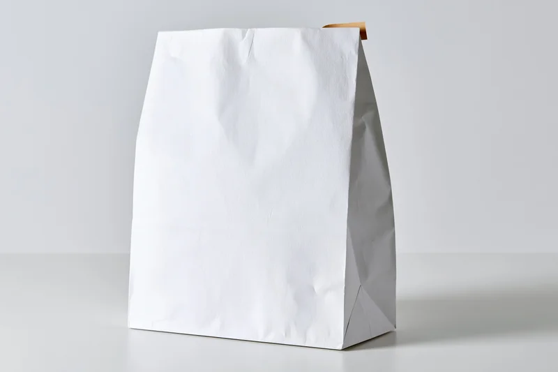 White paper bag standing upright on a white surface with copyspace for branding