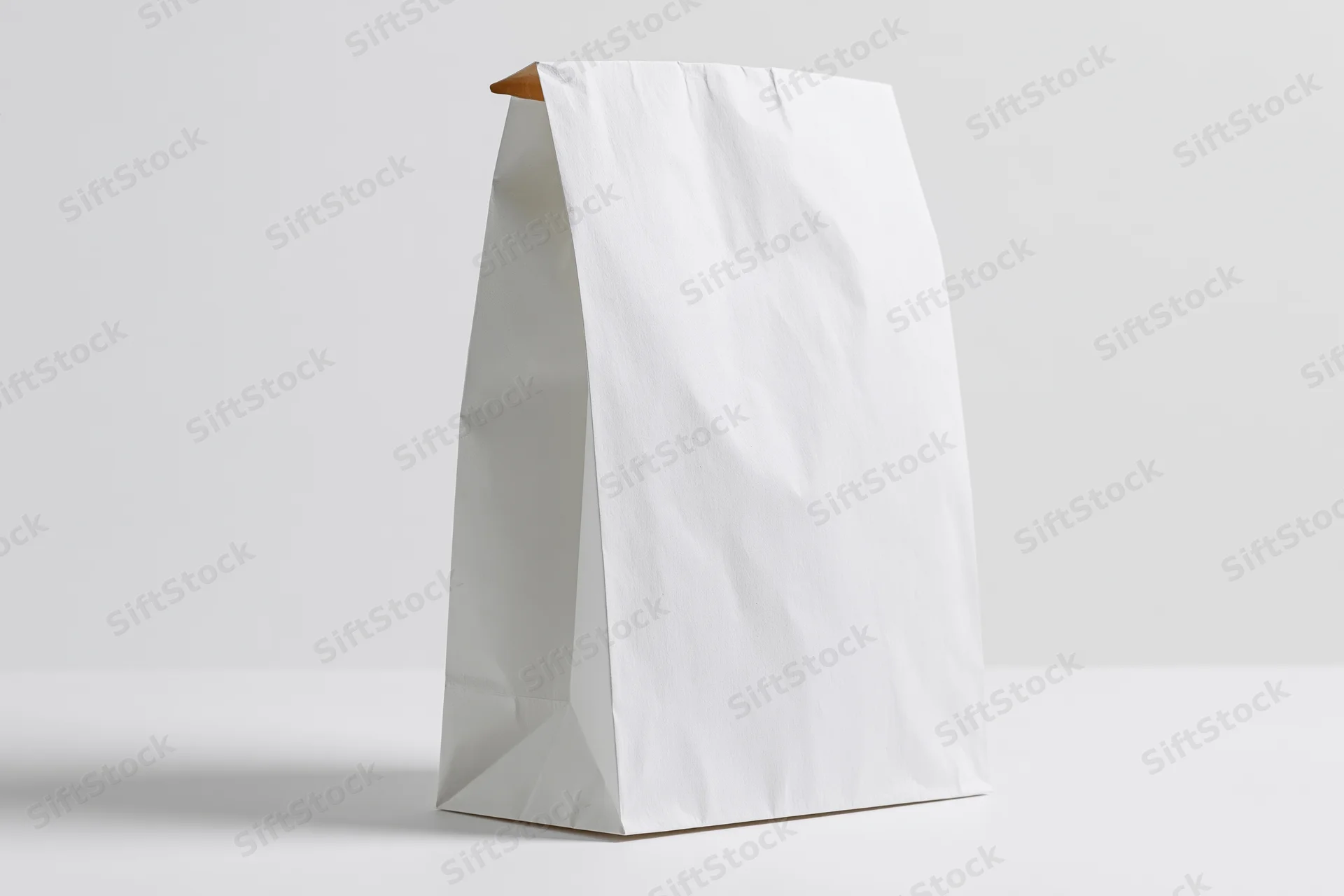 White paper bag standing upright on a white surface with copyspace for branding