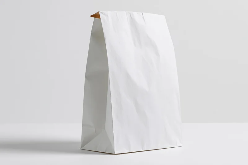 White paper bag standing upright on a white surface with copyspace for branding