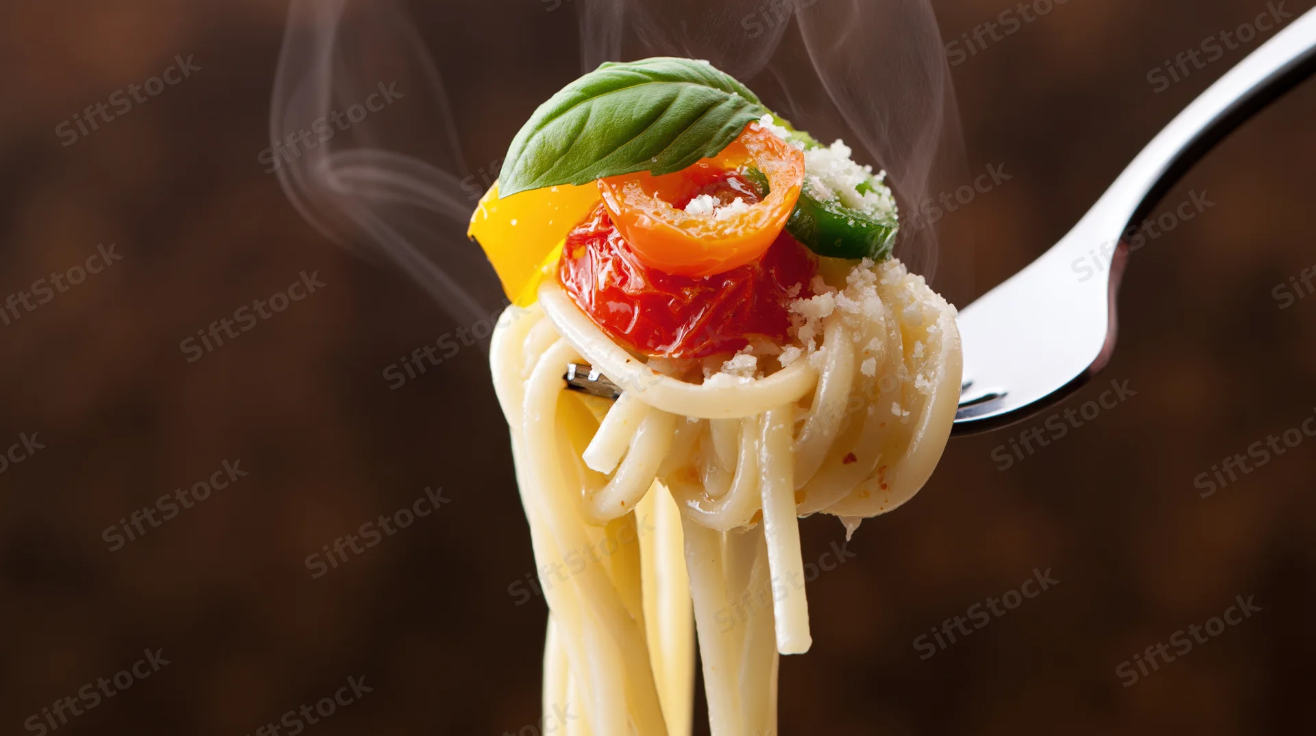 Spaghetti twirled on a fork with cherry tomatoes, basil, and grated cheese, steam rising