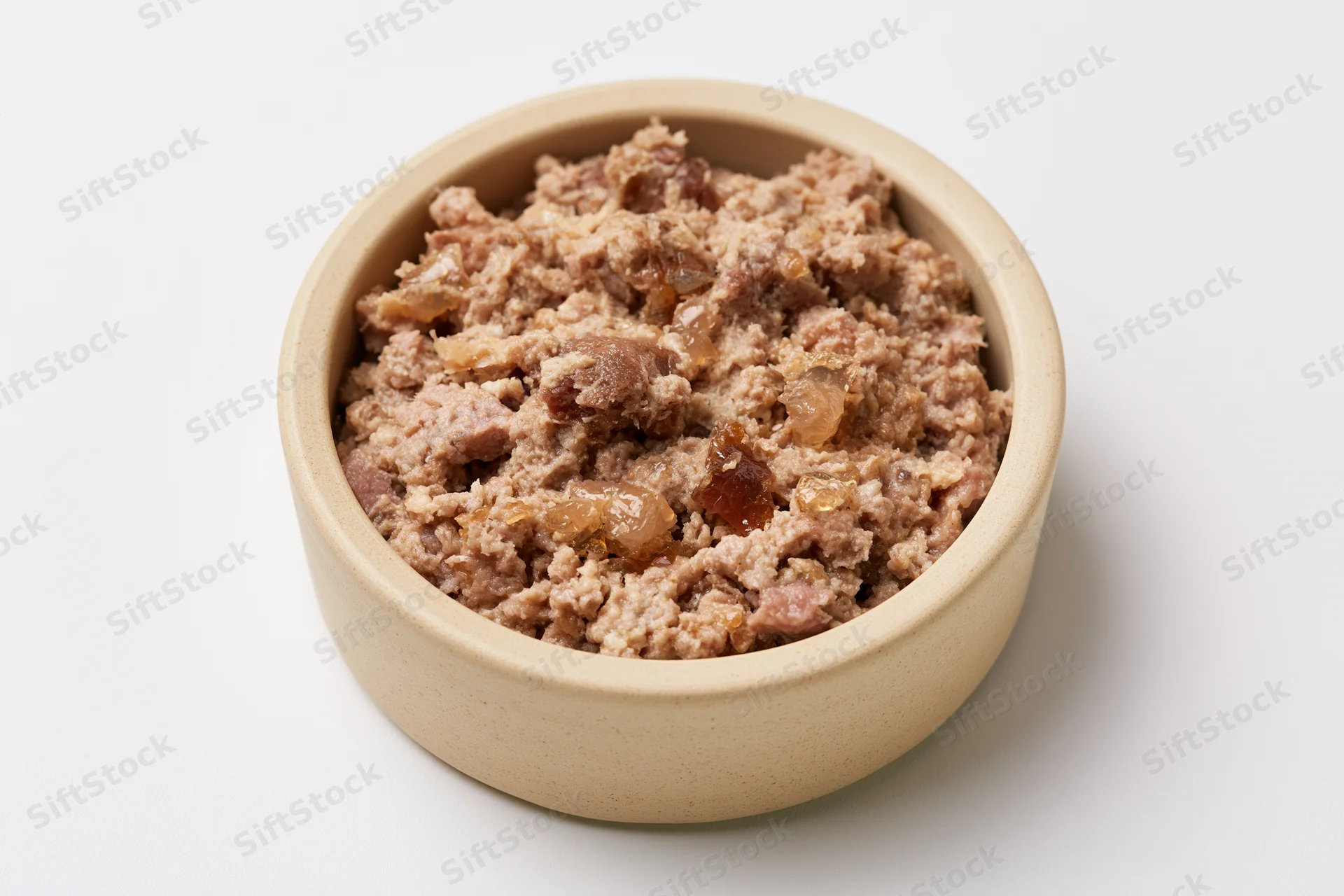 Chunky wet cat food in a small beige ceramic bowl on white background