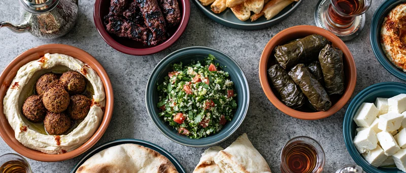 Middle eastern mezze spread with hummus, falafel, tabbouleh, dolma and flatbread on stone countertop