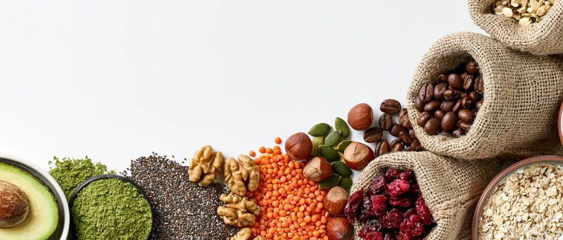 Superfoods and whole ingredients arranged in a flat-lay strip on white background