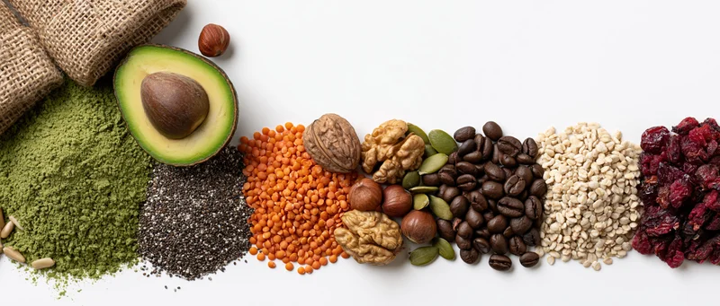 A row of superfoods and whole ingredients arranged on a white surface with copyspace