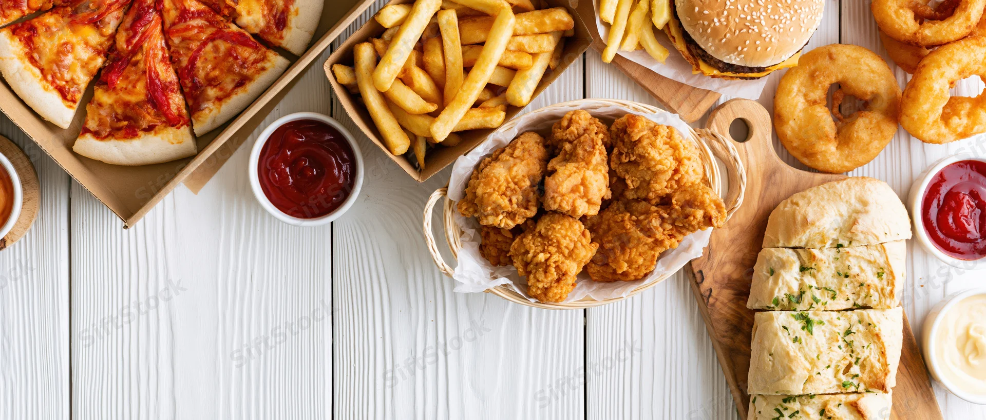 Assorted fast food items arranged on a white wooden table in overhead view